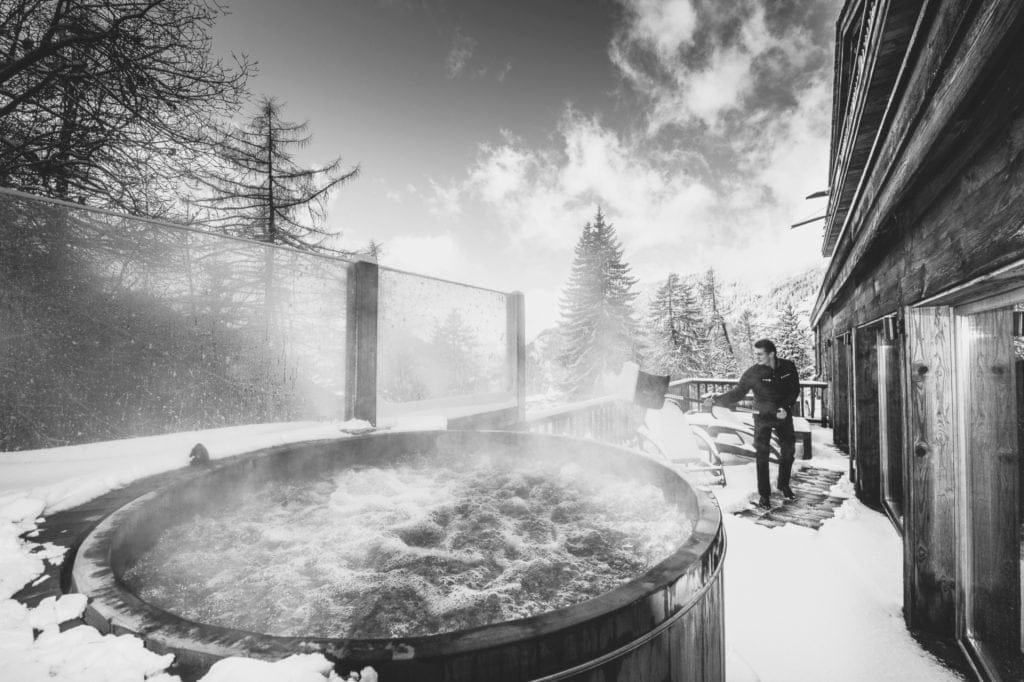 Host clearing snow around a hot tub