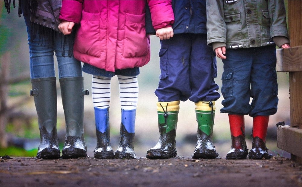 Children standing together in muddy boots